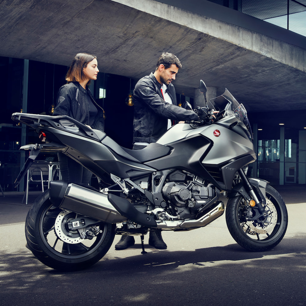 Couple standing next to a Honda motorcycle
